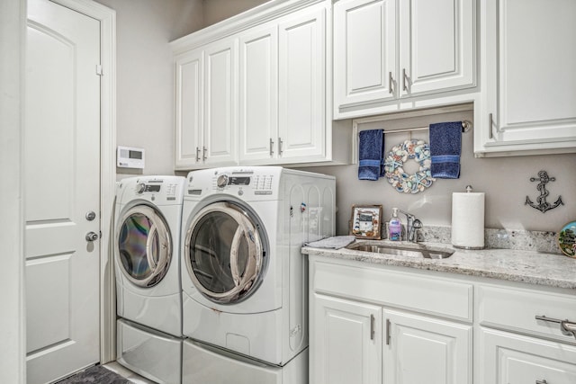 washroom with washer and clothes dryer, cabinet space, and a sink