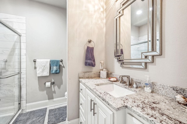 bathroom with vanity, toilet, baseboards, and a stall shower