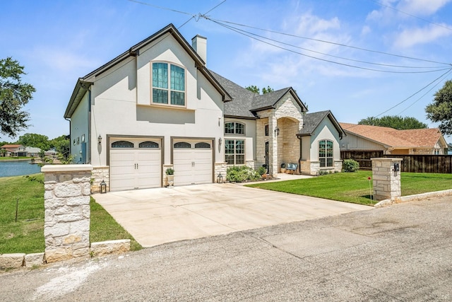 view of front of house with fence, driveway, an attached garage, a front lawn, and stone siding