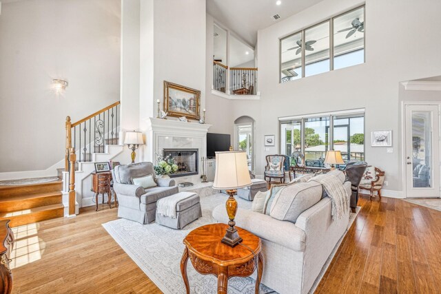 living room with a fireplace, stairs, baseboards, and wood finished floors