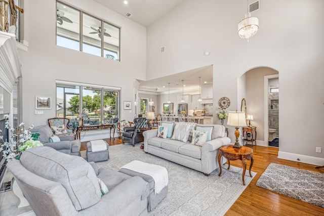 living room featuring arched walkways, visible vents, light wood finished floors, and a wealth of natural light