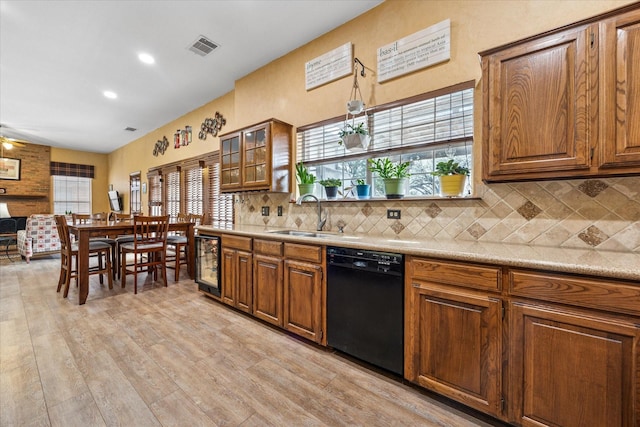 kitchen featuring light wood-style flooring, a sink, decorative backsplash, black dishwasher, and brown cabinets