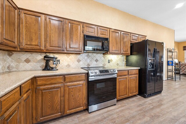 kitchen featuring decorative backsplash, black appliances, light countertops, and brown cabinets