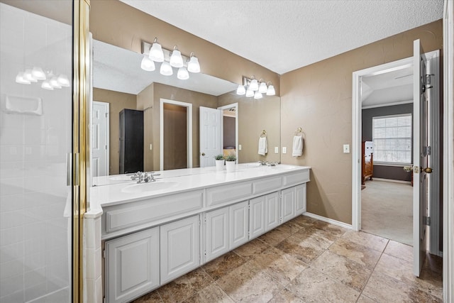 bathroom featuring a sink, baseboards, a textured ceiling, and double vanity