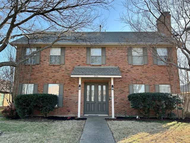 view of front of home featuring brick siding, french doors, and a shingled roof