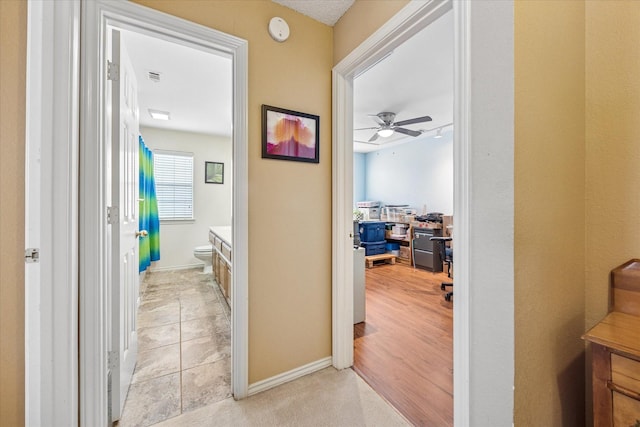 hall featuring baseboards and visible vents