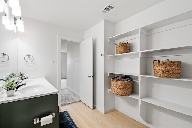 bathroom featuring double vanity, wood finished floors, visible vents, and baseboards