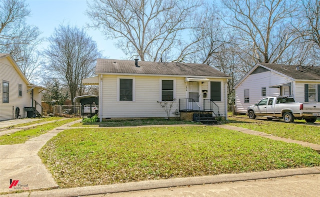 bungalow-style home with a front lawn, driveway, fence, a detached carport, and crawl space