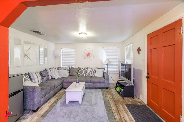 living area with visible vents and wood finished floors