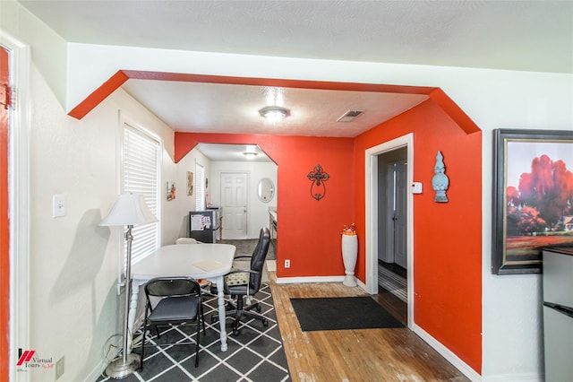 interior space featuring wood finished floors, visible vents, arched walkways, and baseboards