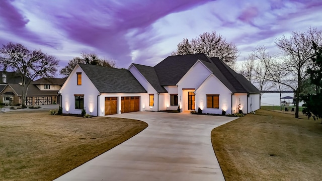 modern farmhouse style home with stucco siding, concrete driveway, and a garage