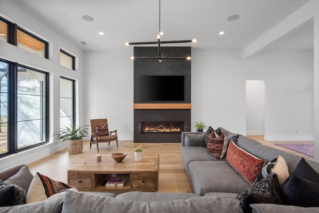 living room featuring recessed lighting, a large fireplace, baseboards, and wood finished floors