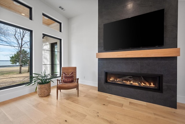 sitting room with visible vents, a fireplace, baseboards, and wood finished floors