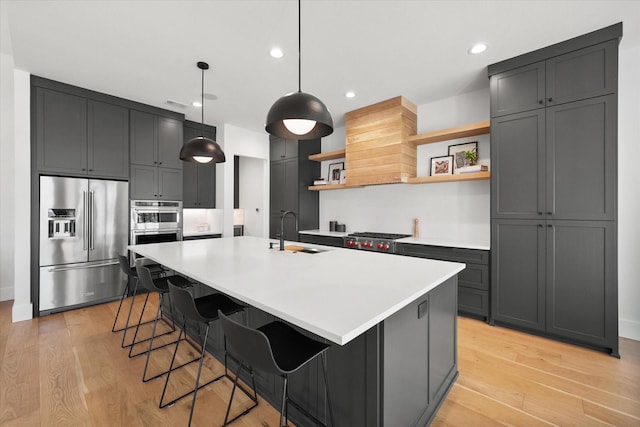 kitchen featuring open shelves, appliances with stainless steel finishes, light wood-style floors, custom exhaust hood, and a sink