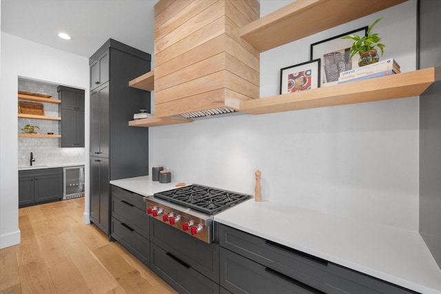 kitchen featuring stainless steel gas stovetop, beverage cooler, light countertops, and open shelves