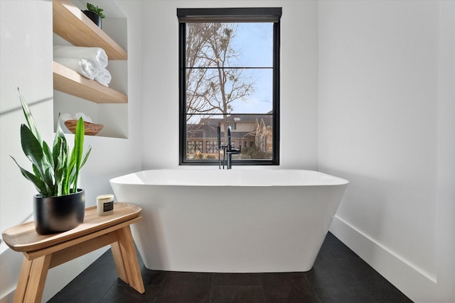 bathroom featuring a freestanding bath, baseboards, and a sink