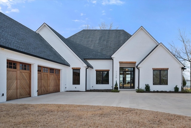 modern farmhouse style home featuring concrete driveway, a garage, and a shingled roof