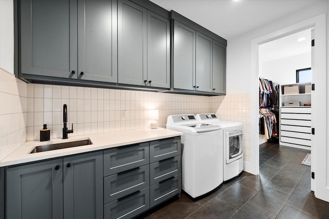 laundry room featuring dark tile patterned floors, cabinet space, independent washer and dryer, and a sink