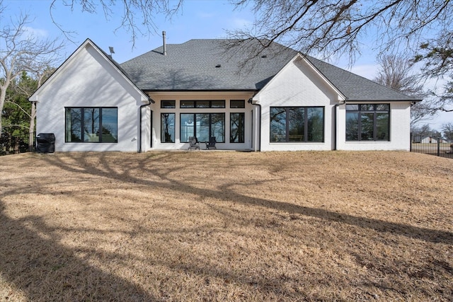 rear view of property with a lawn, roof with shingles, and fence