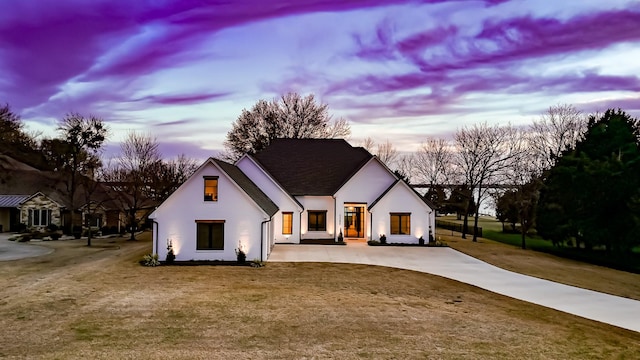 modern farmhouse style home with stucco siding, concrete driveway, and a front lawn