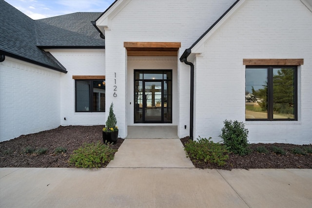 entrance to property with brick siding and roof with shingles