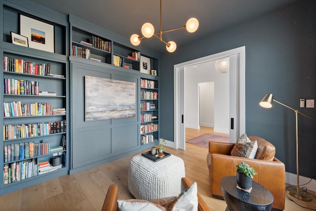 sitting room with an inviting chandelier, baseboards, and light wood finished floors