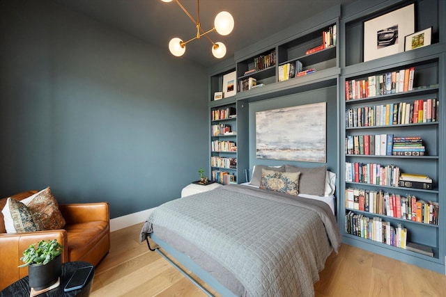 bedroom featuring a notable chandelier, baseboards, and wood finished floors