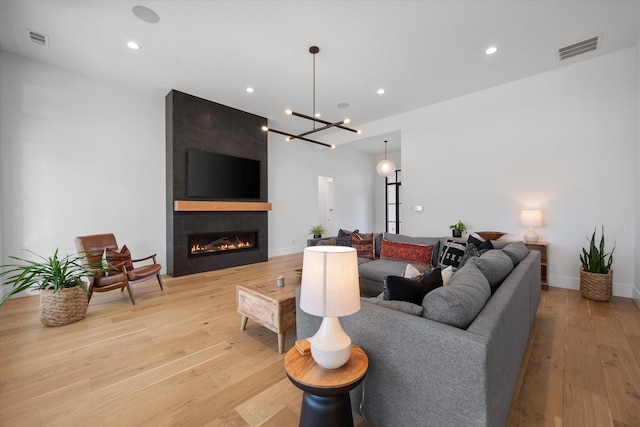 living room featuring recessed lighting, visible vents, a fireplace, and light wood finished floors