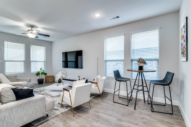 living area with visible vents, baseboards, ceiling fan, and light wood finished floors