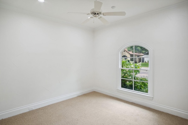 spare room with light carpet, ceiling fan, baseboards, and ornamental molding