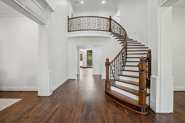 foyer entrance with wood finished floors, baseboards, stairs, crown molding, and a high ceiling
