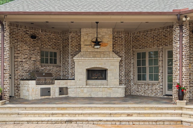 view of patio with grilling area, an outdoor stone fireplace, and an outdoor kitchen