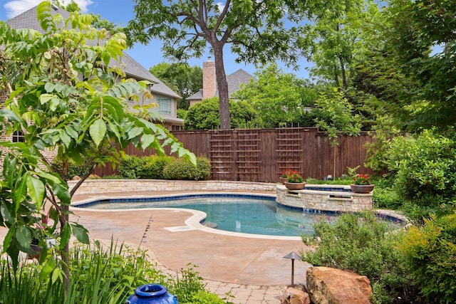 view of pool featuring fence and a pool with connected hot tub