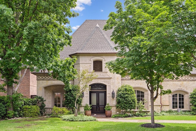 french country style house with stone siding, french doors, and a front yard