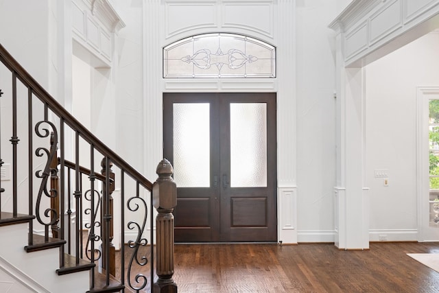 foyer entrance featuring french doors, dark wood-style floors, and stairs