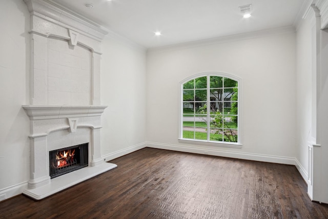 unfurnished living room with dark wood finished floors, a warm lit fireplace, baseboards, crown molding, and recessed lighting
