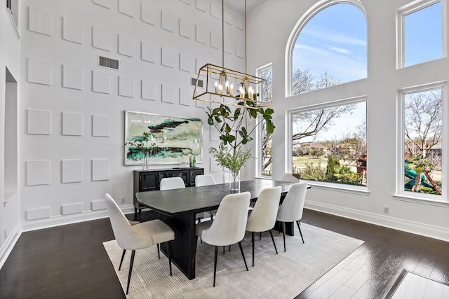 dining area featuring dark wood-type flooring, a notable chandelier, visible vents, and baseboards