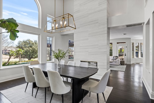 dining space featuring dark wood-style floors, visible vents, baseboards, and a notable chandelier