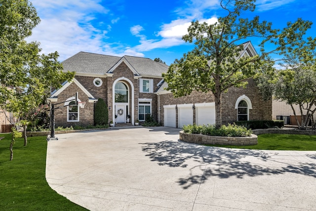 view of front facade featuring brick siding, a front yard, an attached garage, and driveway