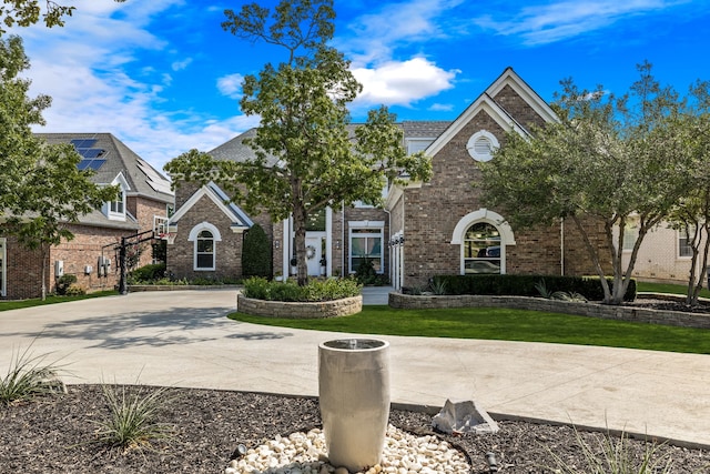 view of front of house featuring a front lawn, brick siding, and curved driveway