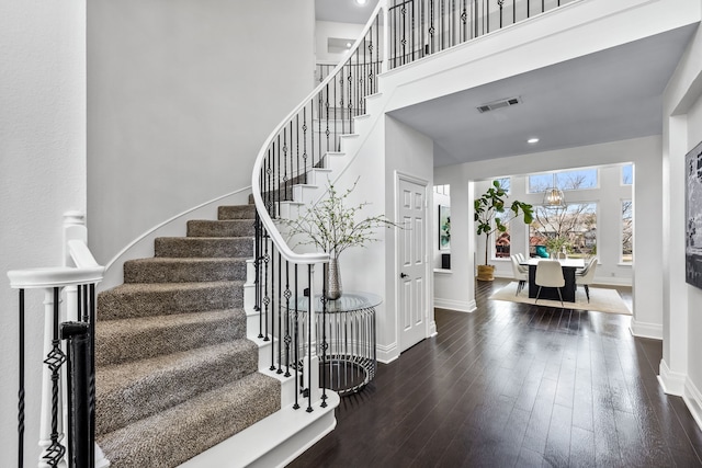 entryway with visible vents, wood finished floors, a high ceiling, baseboards, and stairs