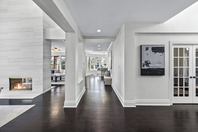 foyer featuring french doors, baseboards, wood finished floors, and a fireplace