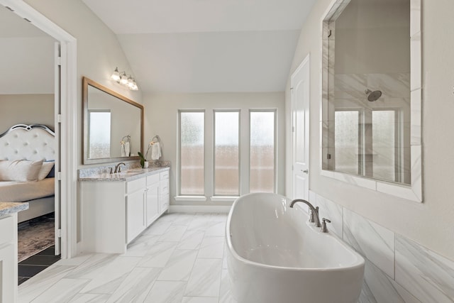 ensuite bathroom with lofted ceiling, a tile shower, ensuite bath, a soaking tub, and vanity