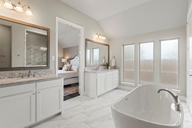 full bathroom featuring vaulted ceiling, a soaking tub, marble finish floor, and a sink