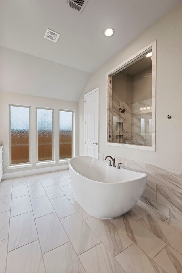 full bath featuring a soaking tub, visible vents, a tile shower, and vaulted ceiling