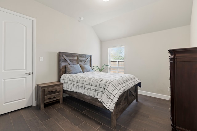 bedroom with dark wood-type flooring, baseboards, and vaulted ceiling