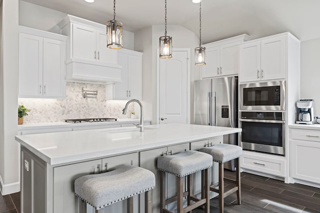 kitchen featuring wood finish floors, premium range hood, decorative backsplash, stainless steel appliances, and a sink