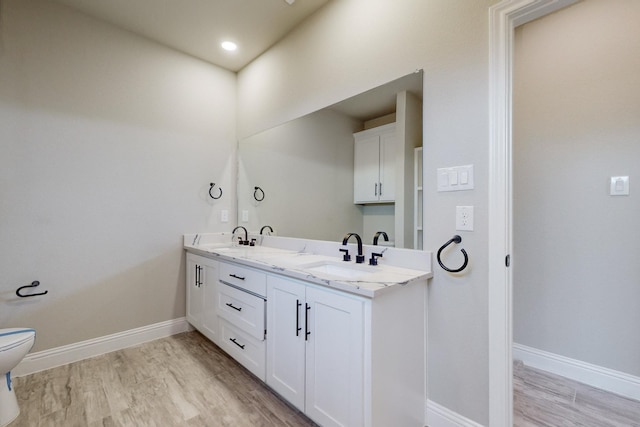 bathroom with double vanity, toilet, baseboards, and a sink