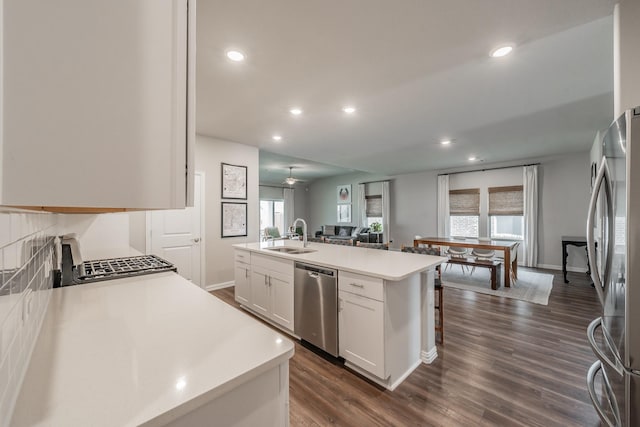 kitchen featuring an island with sink, light countertops, white cabinets, stainless steel appliances, and a sink