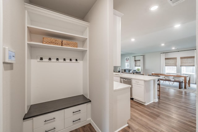 mudroom with recessed lighting, light wood-type flooring, baseboards, and a sink